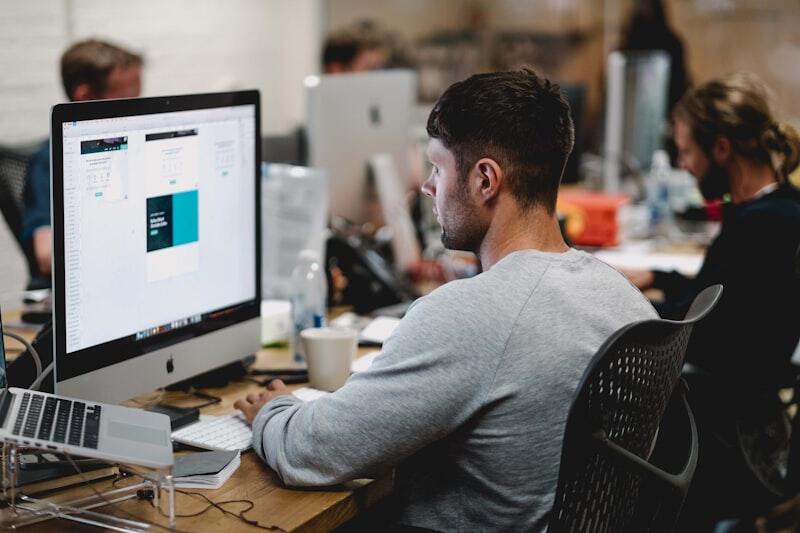 Marketing professional working at desk with analytics on iMac screen